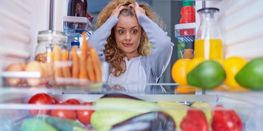 Nachdenkliche Frau vor Kühlrschrank