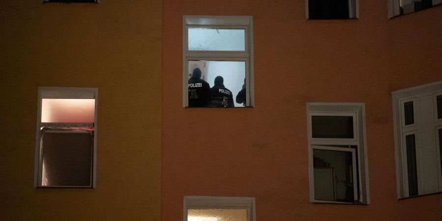 Polizten sind am Morgen im Treppenhaus eines Wohnhauses zu sehen.