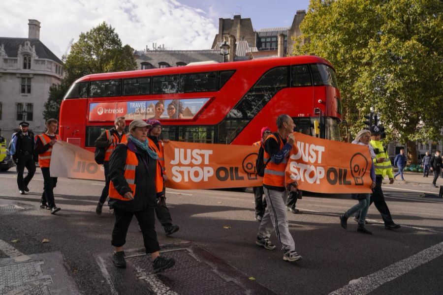 Aktivisten der Gruppe Just Stop Oil halten Transparente, während sie am Mittwoch, 19. Oktober, auf dem Parliament Square in London marschieren.