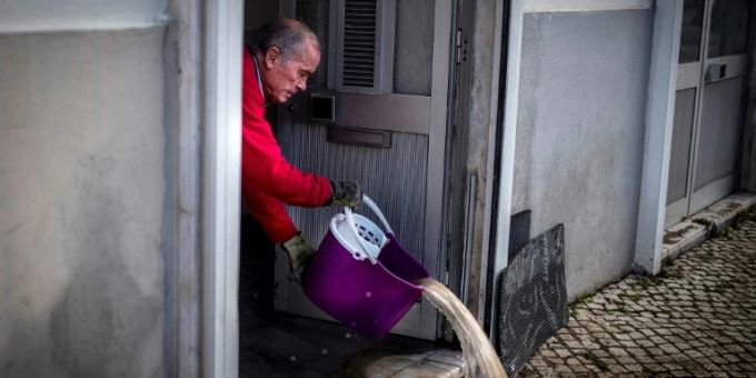 Ein Mann schüttet Wasser aus seinem Geschäft in Lissabon Ein Mann schüttet Wasser aus seinem Geschäft in Lissabon