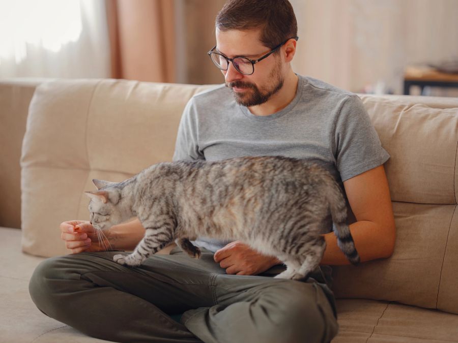 Mann kuschelt mit Katze.