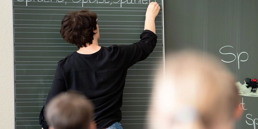 Eine Lehrerin schreibt an die Tafel: An Grundschulen könnte es bald genug Lehrkräfte geben.