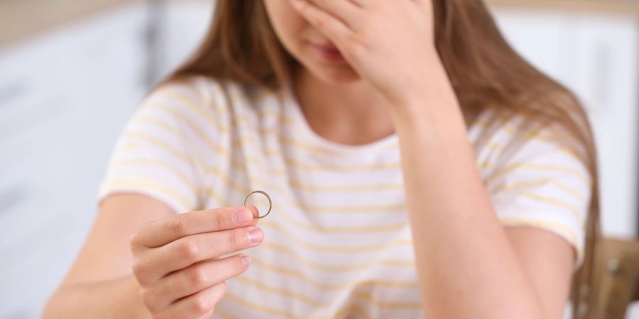 Verzweifelte Frau hält Ring in der Hand