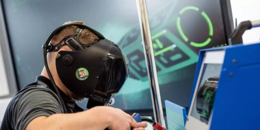 Ein Auszubildender arbeitet im Daimler-Ausbildungszentrum in einem neuen Industrie-4.0-Labor an einer virtuellen Schweissmaschine. Foto: Christoph Schmidt/dpa