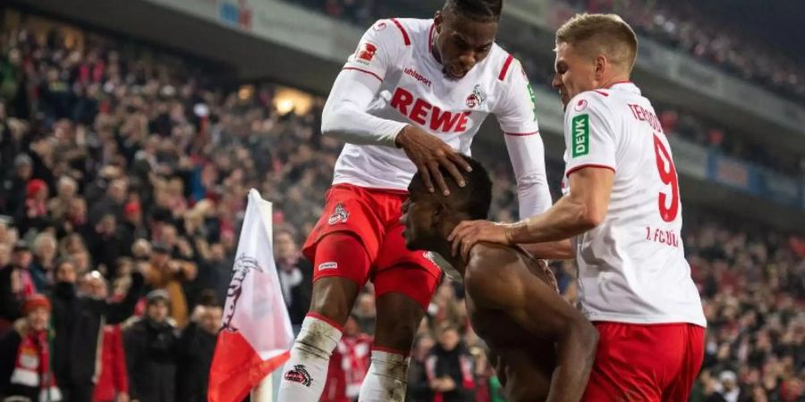 Die Kölner Kingley Ehizibue (l) und Simon Terodde (r) feiern mit Torschütze Jhon Cordoba den Treffer zum 1:1 Ausgleich. Foto: Marius Becker/dpa