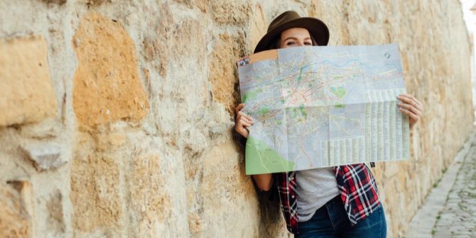 Frau Landkarte Wanderoutfit Wand gelehnt