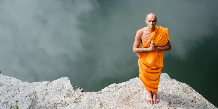 buddhistischer mönch meditiert, see, felsen