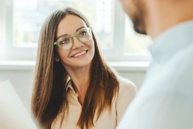 Frau mit Brille lächelt Kollegen an