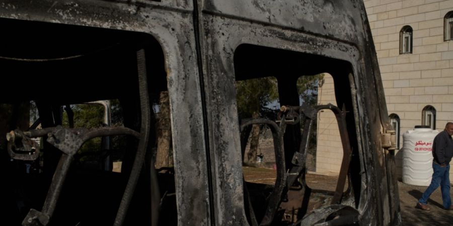 ARCHIV - Moussab Mshala geht an einem Fahrzeug vorbei, das bei einem Angriff israelischer Siedler vor seinem Haus im Westjordanlanddorf al-Jab'a in der Nähe von Bethlehem verbrannt ist...