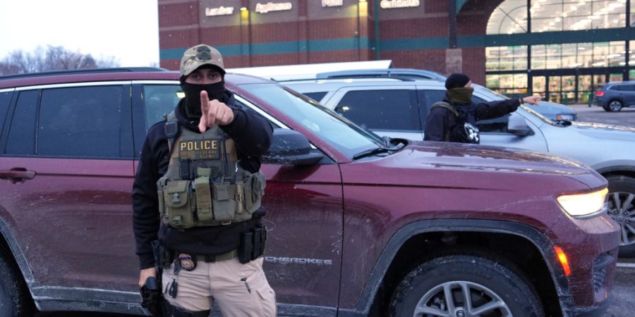 Ein ICE-Beamter warnt einen Fotografen, zurückzubleiben, während eine Person festgenommen wird. Foto: Adam Gray/AP/dpa