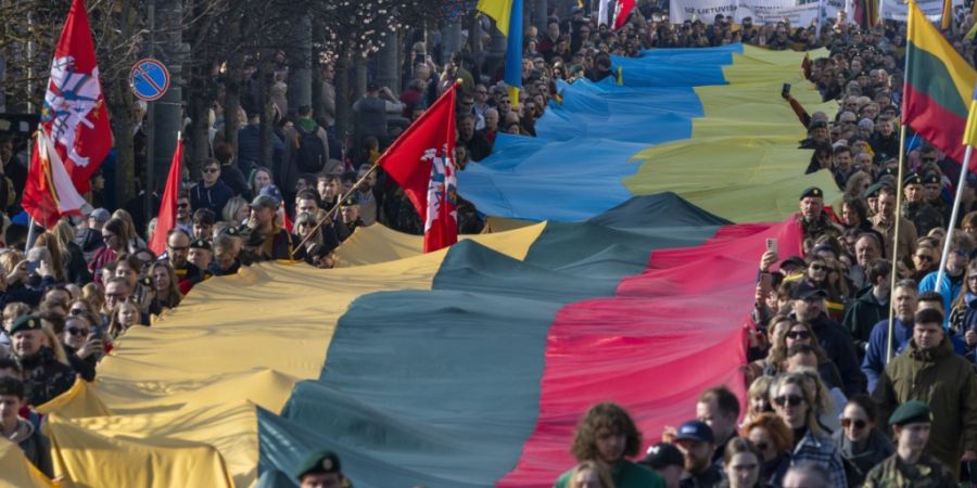 ARCHIV - Während einer Feier zum 35. Jahrestag der Unabhängigkeit Litauens von der Sowjetunion, tragen Menschen eine riesige ukrainische und eine litauische Fahne, um gegen den russis...
