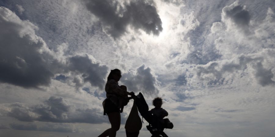 Eine Frau spaziert mit ihrem Kinderwagen am Strand Ciudad JardÌn auf Mallorca entlang. Foto: Clara Margais/dpa/Symbolbild