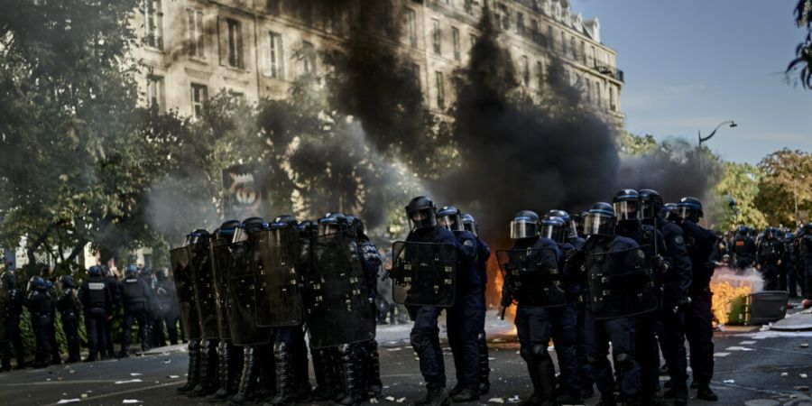 ARCHIV - Polizisten stehen bei Protesten gegen unterfinanzierte Schulen in Paris auf der Straße während hinter ihnen Mülltonnen brennen. Foto: Antonin Burat/Le Pictorium via ZUMA Pre...
