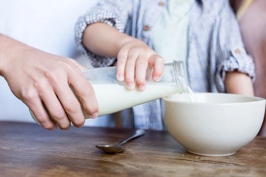 Vater und Kind schenken Milch in Schüssel ein