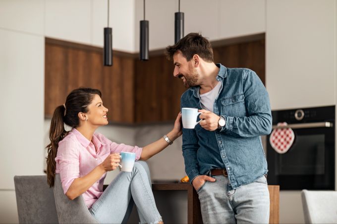 Nicht nur körperliche Nähe, sondern auch regelmässige Kommunikation zählt. Paar trinkt Kaffee und unterhält sich in der Küche, lachen, Austausch