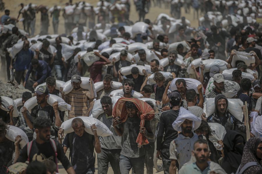 Bürger des Gazastreifens tragen Mehlsäcke, die sie an einer Essensvergabe erhalten haben.