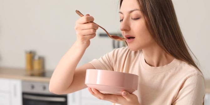 Frau beim Essen mit Löffel und Schüssel