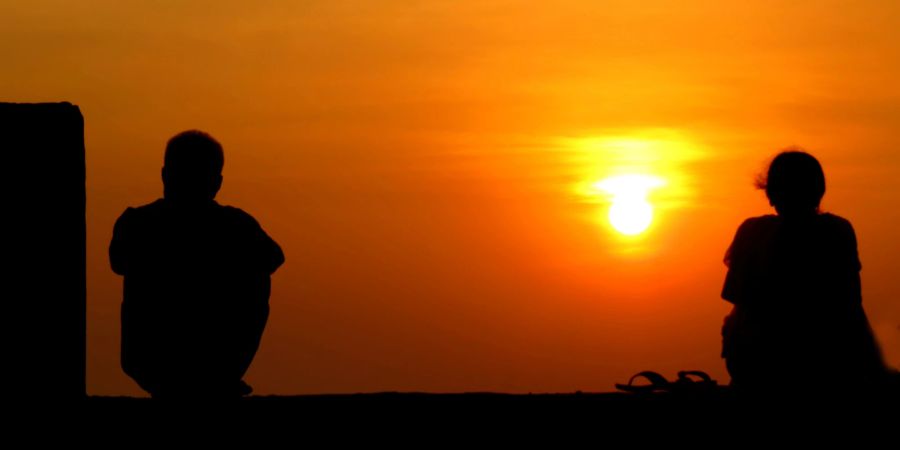 paar im sonnenuntergang, sitzt getrennt voneinander