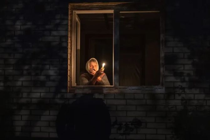 Ukrainische Frau mit Kerze am Fenster