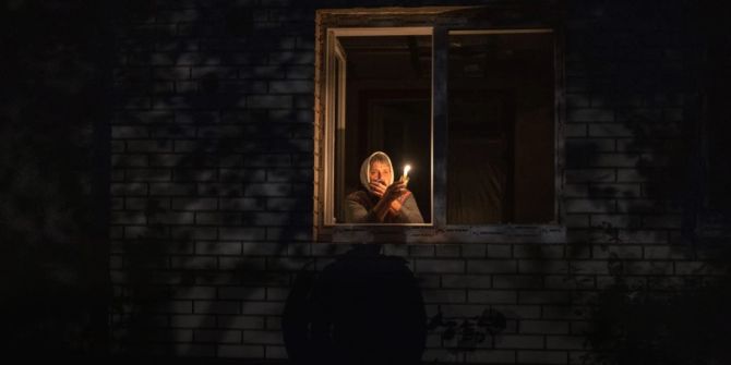 Ukrainische Frau mit Kerze am Fenster