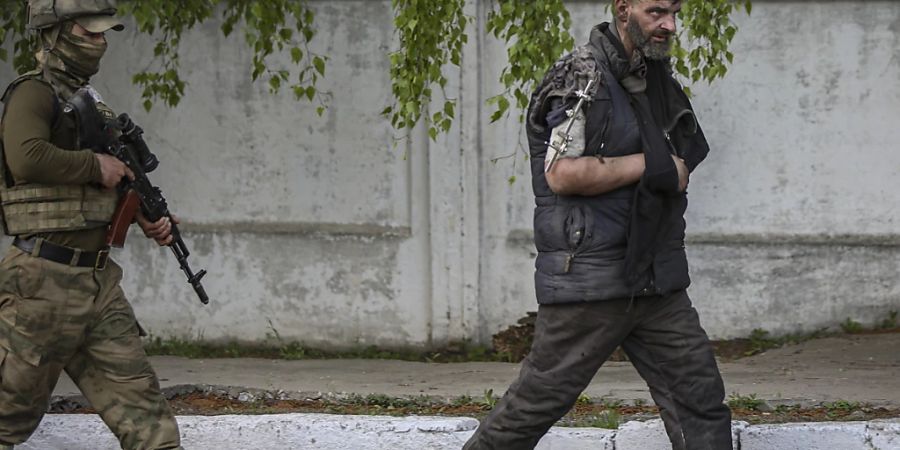 Ein russischer oder pro-russisch-separatistischer Soldat (links) führt einen Kämpfer des ukrainischen Asow-Regiments aus dem Stahlwerk in Mariupol ab. (Aufnahme vom 17. Mai 2022)