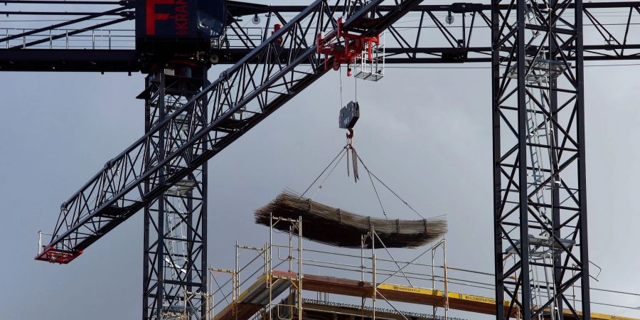An einem Baukran wird Baumaterial auf einer Baustelle des Quartiers Heidestrasse in Berlin transportiert.