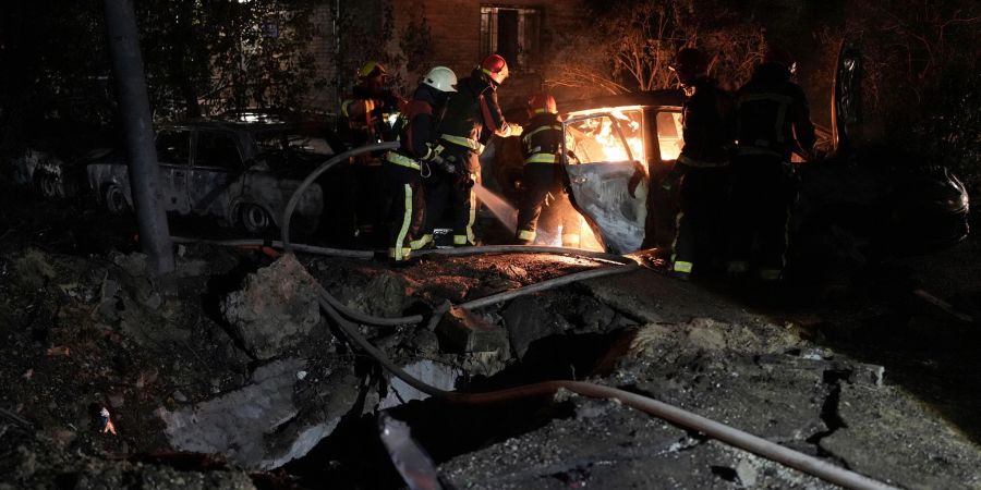 Rettungskräfte löschen in einem geparkten Auto ein Feuer, das nach einem russischen Luftangriff im Kiewer Pecherskyi-Viertel durch herabfallende Trümmer verursacht wurde.