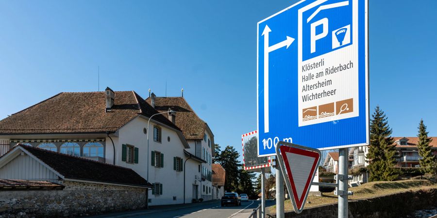 Das Wichterheergut (Mandach-Gut) in Oberhofen ist ein ehemaliges Reb- und Herbsthaus direkt am Thunersee. Im Vordergrund die Seestrasse und ein Wegweiser zum Parkhaus.