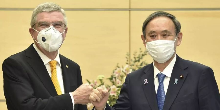 IOC-Präsident Thomas Bach (l) und Japans Premierminister Yoshihide Suga begrüssen sich. Foto: Kazuhiro Nogi/Pool AFP/AP/dpa