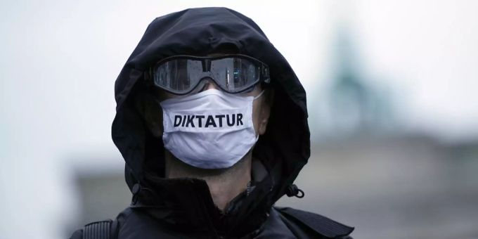 Ein Teilnehmer einer Demonstration gegen die Corona-Einschränkungen der Bundesregierung trägt vor dem Brandenburger Tor eine Mund-Nasen-Bedeckung mit der Aufschrift «Diktatur». Antisemitismus coronavirus protest