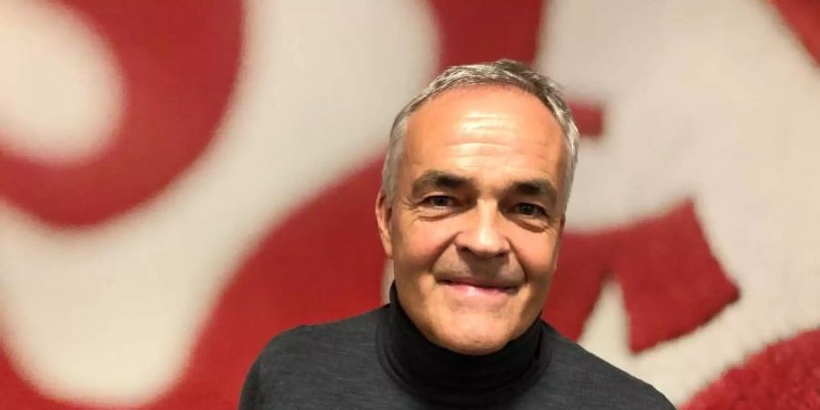 Der Vorsitzende des Vereinsbeirats des VfB Stuttgart, Wolf-Dietrich Erhard, steht vor einem grossen Vereinswappen. Foto: Maximilian Haupt/dpa