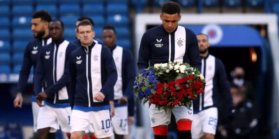 James Tavernier von den Glasgow Rangers trägt vor Spielbeginn einen Kranz auf das Feld. Foto: Andrew Milligan/PA Wire/dpa