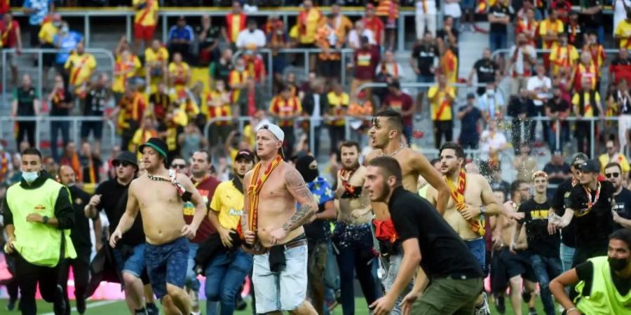 Fans von RC Lens und OSC Lille stürmen auf das Spielfeld des Stade Bollaert-Delelis. Foto: Francois Lo Presti/AFP/dpa