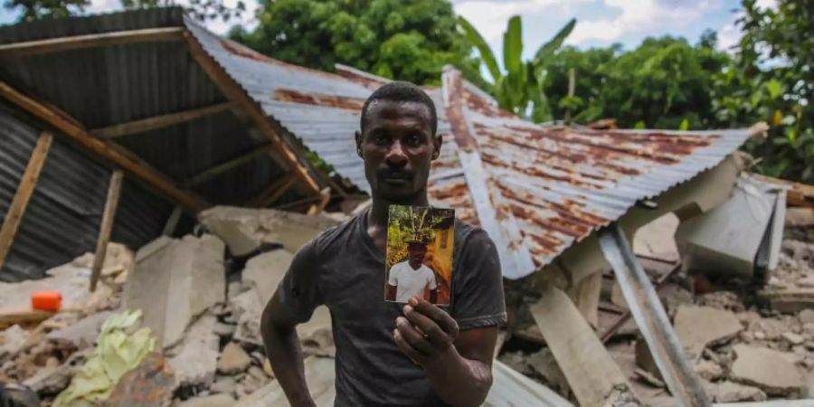 Ein Haitianer mit einem Foto seines bei dem Erdbeben ums Leben gekommenen Bruders. Foto: Joseph Odelyn/AP/dpa