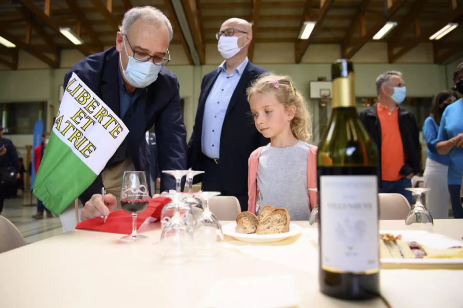 Bundespräsident Guy Parmelin gibt einem Mädchen ein Autogramm auf einer Schweizer Fahne, während dem Apéro mit der Bevölkerung auf der Bundesratsreise, am 1. Juli 2021 im Sportzentrum des Vallée du Joux.