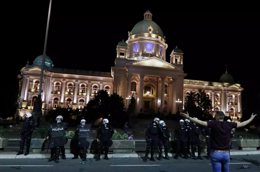 Polizisten bewachen das Parlamentsgebäude, während Demonstranten gegen die Ankündigung des serbischen Präsidenten protestieren.