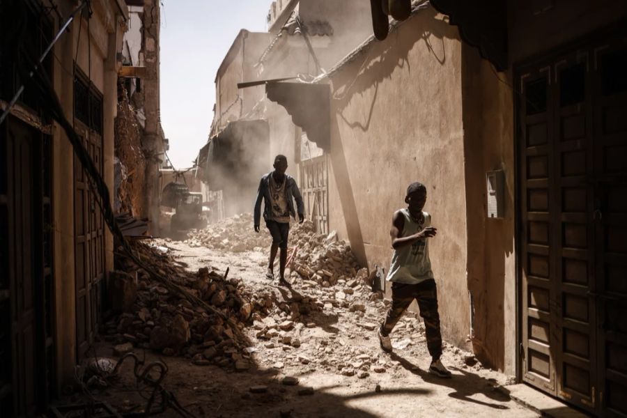 Zwei Männer bahnen ihren Weg durch eine Trümmergasse in Marrakesch, Marokko.