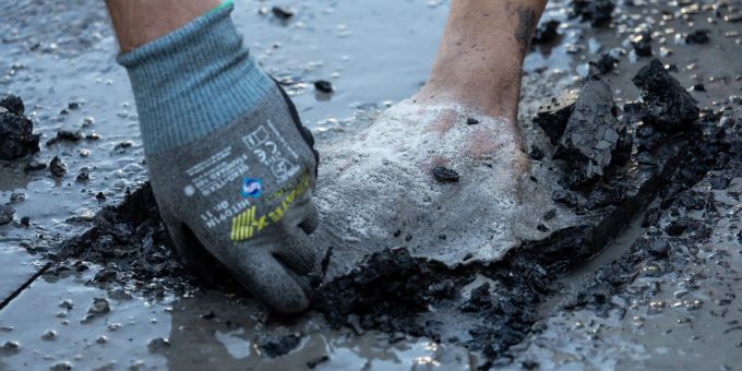 Ein Polizist entfernt Asphalt, um einen Aktivisten von der Strasse zu lösen. Ein Polizist entfernt Asphalt, um einen Aktivisten von der Strasse zu lösen.