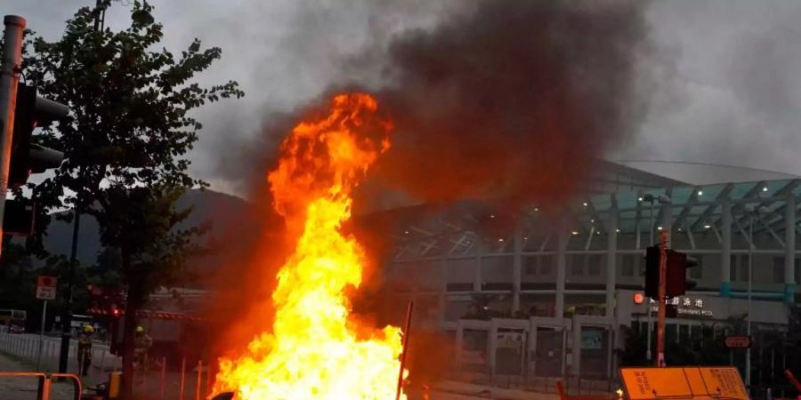 Von prodemokratischen Demonstranten vor dem Flughafen errichtete Barrikaden stehen in Flammen. Foto: Vincent Yu/AP