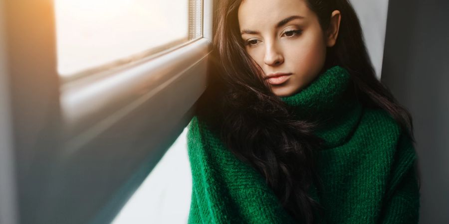 frau schaut traurig aus dem fenster