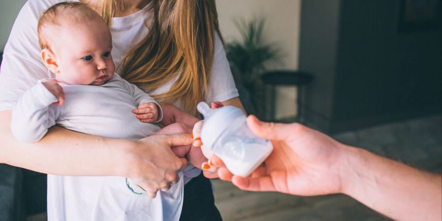 Baby mit Mutter bekommt Milchflasche gereicht