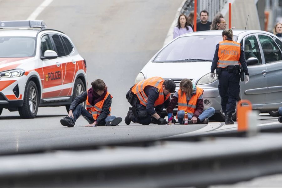 Die Polizei befreit angeklebte Klima-Aktivisten von einer Strasse.