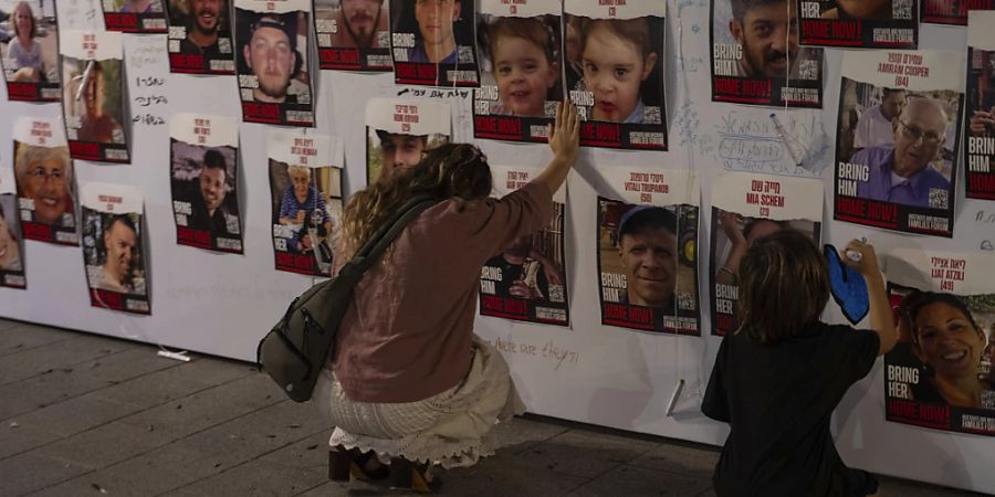 dpatopbilder - Eine israelische Frau berührt Fotos von in Gaza vermissten und gefangen gehaltenen Israelis.