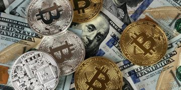 Physische Bitcoin-Münzen liegen auf US-amerikanischen Dollarscheinen verteilt.