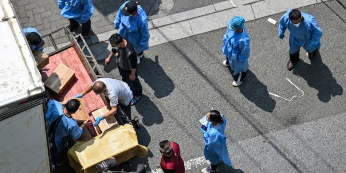 Arbeiter in Corona-Schutzkleidung entladen einen Lkw Arbeiter in Corona-Schutzkleidung entladen einen Lkw