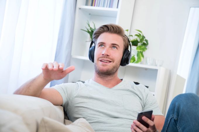 Kopfhörer auf, Musik laut: Die Playlist mit den liebsten Songs kann zu besserer Stimmung verhelfen. Mann Sofa Kopfhörer Musik