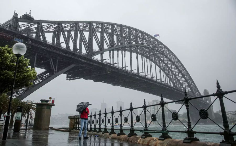 Ein Mann versucht, sich mit einem Regenschirm vor dem Regen und Sturm in Sydney zu schützen. Schwere Unwetter haben weite Teile Australiens heimgesucht.