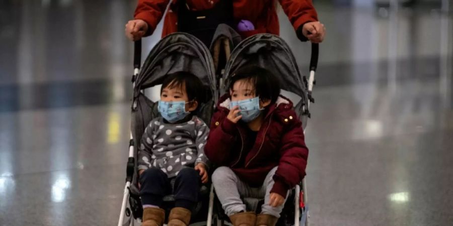 Kinder mit Atemschutzmasken am Flughafen von Peking