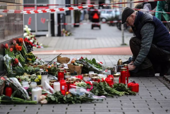 Ein Mann legt Blumen nieder. Hanau