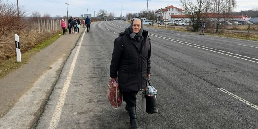 Eine ältere Frau läuft auf der Strasse in der Nähe der ungarisch-ukrainischen Grenze